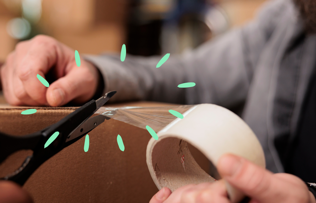 Person sealing a cardboard moving box with packing tape.